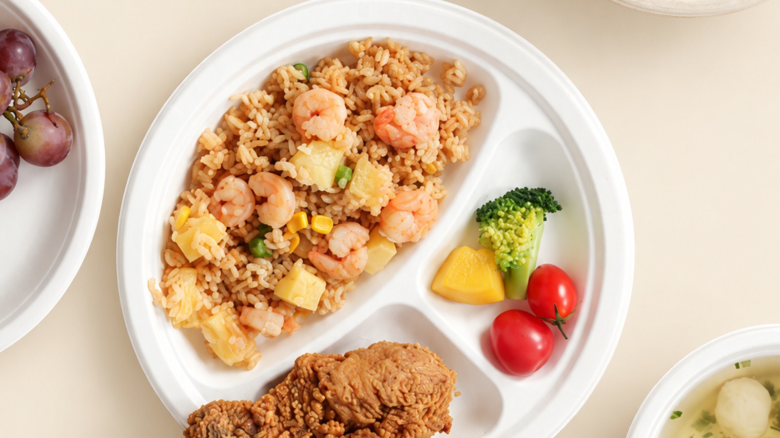 Molded fiber tableware serving rice, fried chicken, vegetables, fruit and side dishes