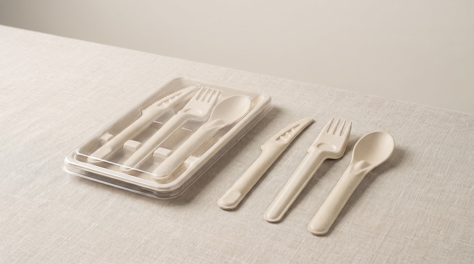 Individually wrapped plant fiber cutlery sets beside loose bulk pieces